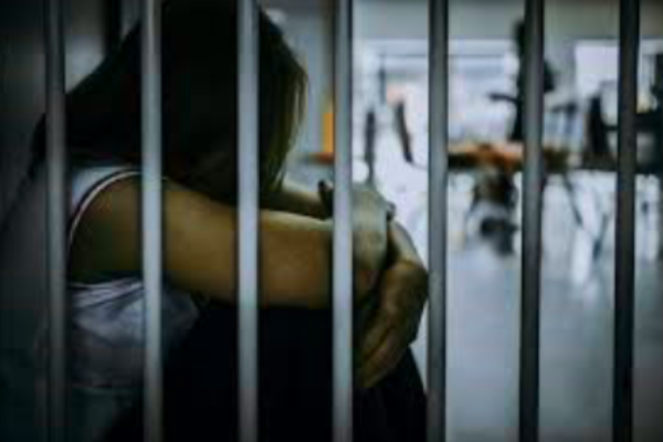Incarcerated woman in prison, head on knees.